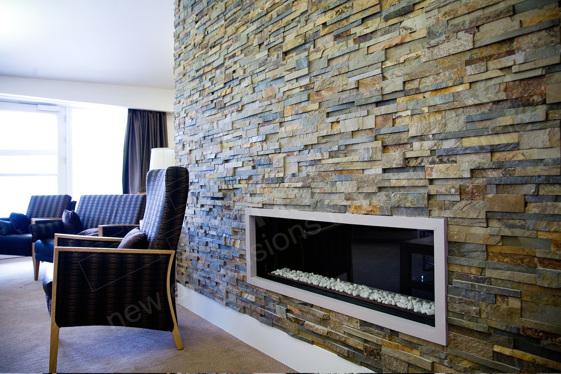 Norstone Ochre Blend Rock Panels used on a floor to ceiling fireplace with long linear gas fireplace insert